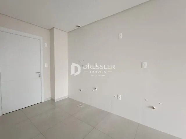 Vista interna de um corredor com paredes brancas e piso cinza claro.