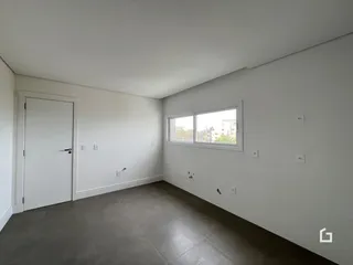Ambiente interno de uma sala com paredes brancas e piso cinza.