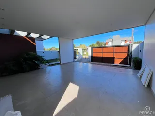 Vista externa de uma área pavimentada adjacente à garagem de uma residência.
