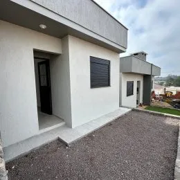 Fachada externa de uma casa moderna em Lajeado, Brasil, com paredes brancas e revestimento escuro.