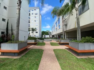 Vista externa de um complexo residencial com paisagismo e palmeiras.