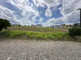 Vista externa de uma área gramada com residências ao fundo.