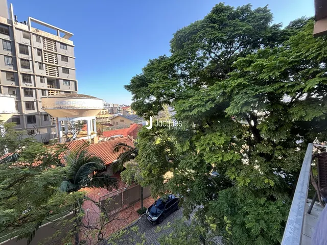 Vista aérea de um imóvel com vegetação densa e edifícios ao fundo.