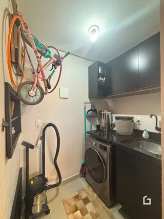 Foto de uma área interna com armários escuros e máquina de lavar roupa.