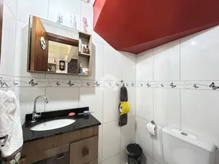 Foto de um banheiro com revestimento cerâmico e bancada escura.