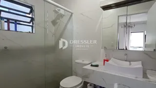 Foto de um banheiro com revestimento em mármore e louças brancas.