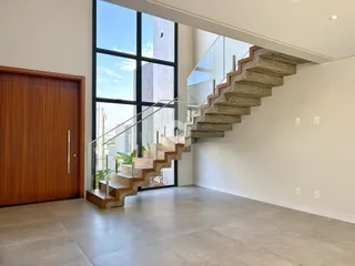 Ambiente interno moderno com grandes janelas e escadaria de concreto.
