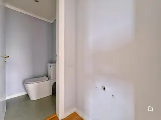 Vista de um corredor interno com um vaso sanitário branco.