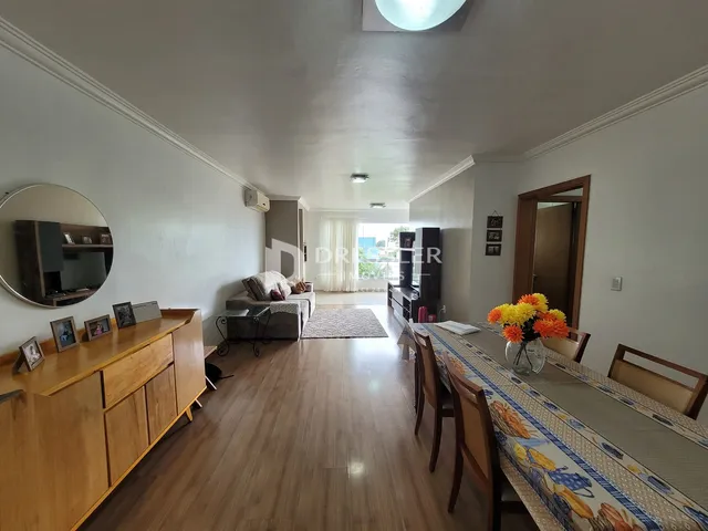 Sala de estar e jantar com piso de madeira clara em um imóvel em Lajeado.