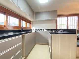 Vista interna de uma cozinha moderna com armários e bancadas escuras.