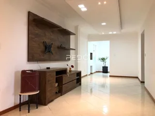 Uma sala de estar com parede de madeira escura e piso claro.