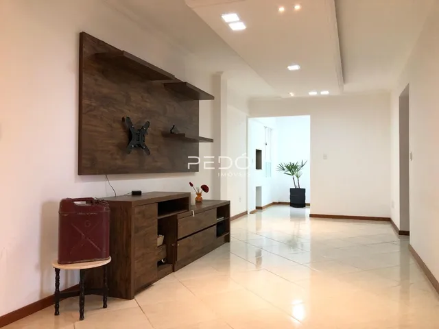 Uma sala de estar com parede de madeira escura e piso claro.
