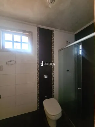 Interior de um banheiro com revestimento de azulejos brancos e porta escura.