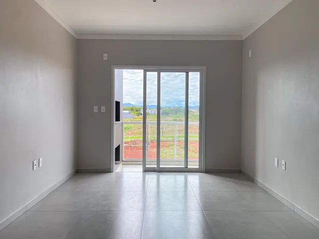Vista de um interior com portas de vidro que dão para uma área externa com terra nua.