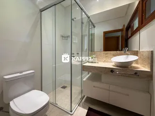 Foto de um banheiro com box de vidro e bancada de mármore.