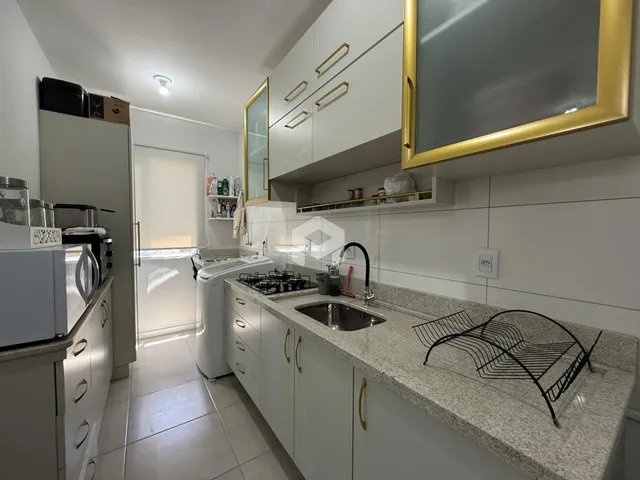 Vista da cozinha com armários brancos e bancada de granito.