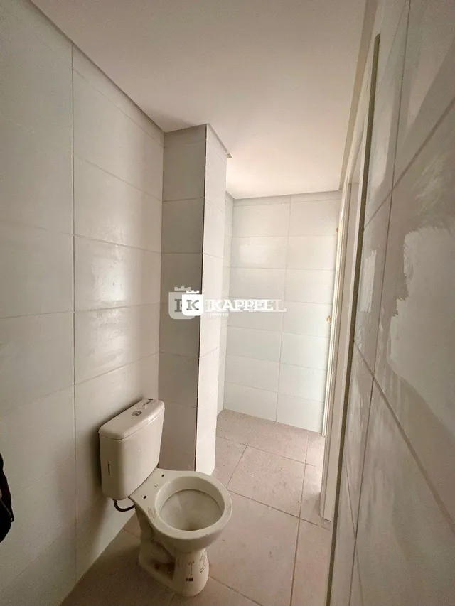 Foto interna de um banheiro com revestimento de azulejos brancos.