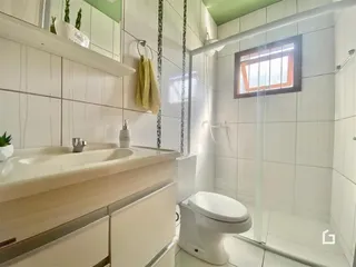 Foto de um banheiro com revestimento branco e box de vidro.