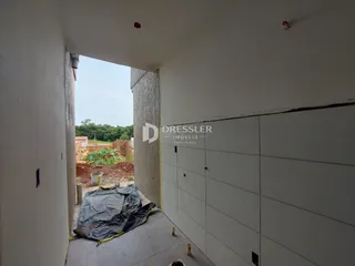 Vista de um corredor interno que se abre para uma área externa em construção.