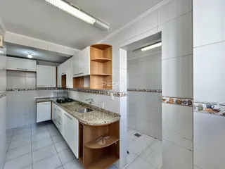 Cozinha com armários de madeira e revestimento branco.