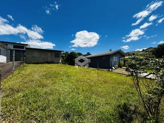 Vista externa de uma propriedade com gramado verde e dois edifícios ao fundo.
