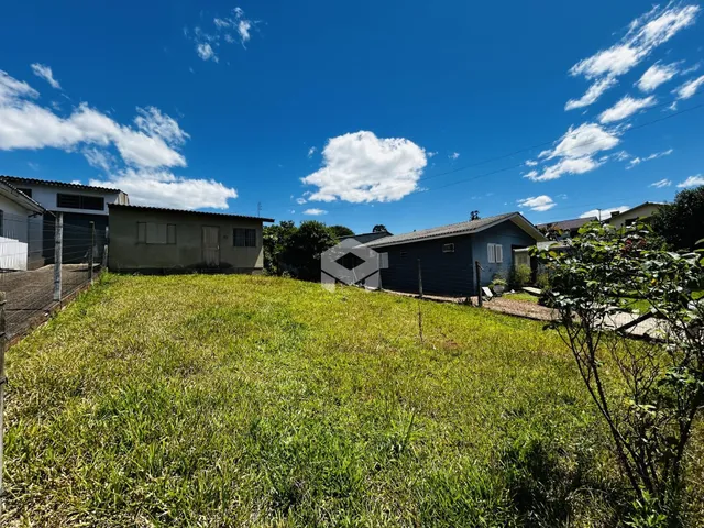 Vista externa de uma propriedade com gramado verde e dois edifícios ao fundo.