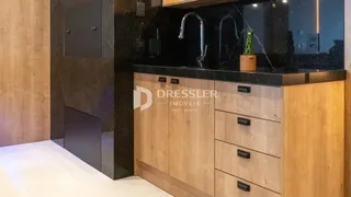 Detalhe da cozinha com armários escuros e bancada de granito.