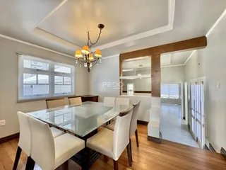 Sala de jantar com mesa de vidro e piso de madeira.