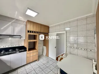Cozinha com armários brancos e piso de cerâmica clara.