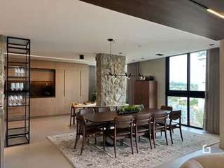 Sala de jantar moderna com parede de pedra e grandes janelas.