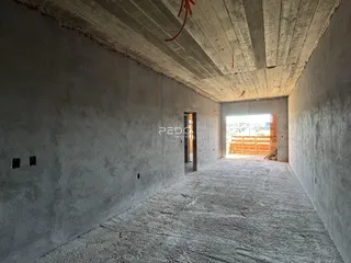 Corredor interno com paredes de concreto aparente e teto cru.