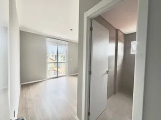 Hall de entrada com piso de madeira clara e porta de vidro que dá para o exterior.