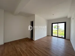 Interior de uma sala com piso de madeira clara e porta de vidro.