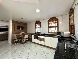 Interior da cozinha e sala de jantar com armários de madeira e piso de cerâmica.
