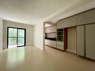 Sala de estar com cozinha integrada e porta de vidro.