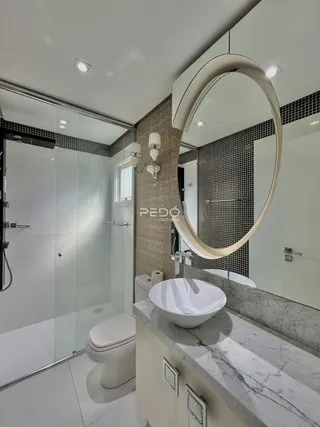 Banheiro moderno com box de vidro, pia de mármore e revestimento de azulejos.