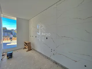 Parede interna com revestimento de mármore e piso de concreto em obra.