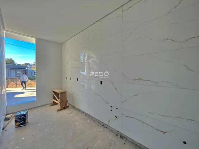 Parede interna com revestimento de mármore e piso de concreto em obra.