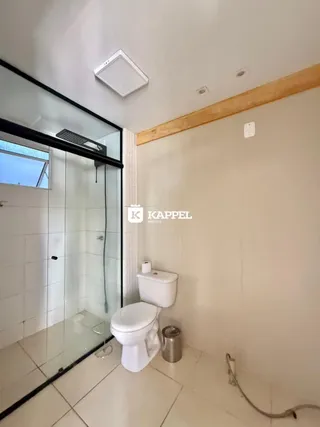Banheiro com box de vidro e piso cerâmico.