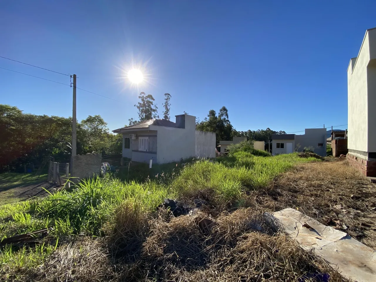 Fachada de uma casa residencial em Lajeado, Brasil, com vegetação alta no primeiro plano.