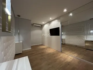 Imagem de uma sala de estar com piso de madeira clara e paredes brancas.