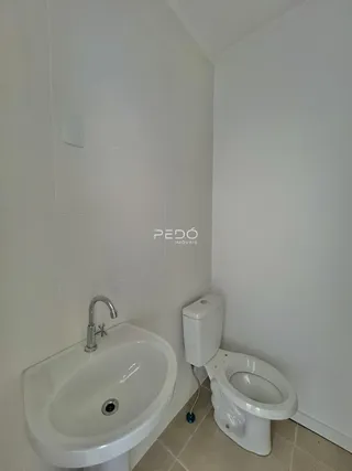 Foto de um banheiro com pia e vaso sanitário em cerâmica branca.