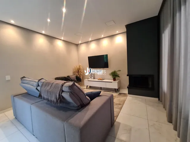 Sala de estar moderna com sofá e televisão em um ambiente claro.