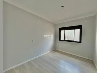 Ambiente interno de uma sala com piso de madeira clara e parede branca.