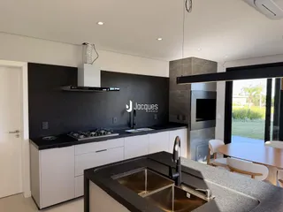 Cozinha moderna com armários pretos e bancada escura em imóvel no Brasil.