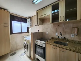 Cozinha com armários de madeira clara e bancada de granito.