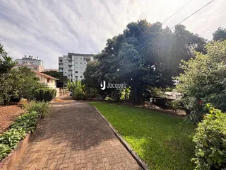 Vista da entrada de uma propriedade com jardim e vegetação.