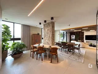 Ambiente interno de uma sala de estar com grandes janelas e piso claro.