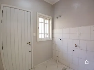 Corredor interno com piso cerâmico e paredes brancas.