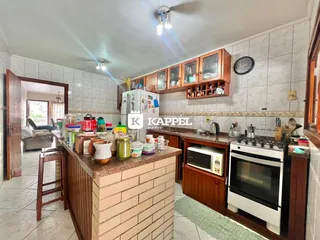 Foto interna de uma cozinha com armários de madeira e bancada de pedra.